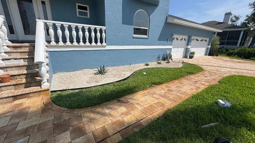 Modern blue house exterior with landscaped pathway, gravel yard, and lush green grass.